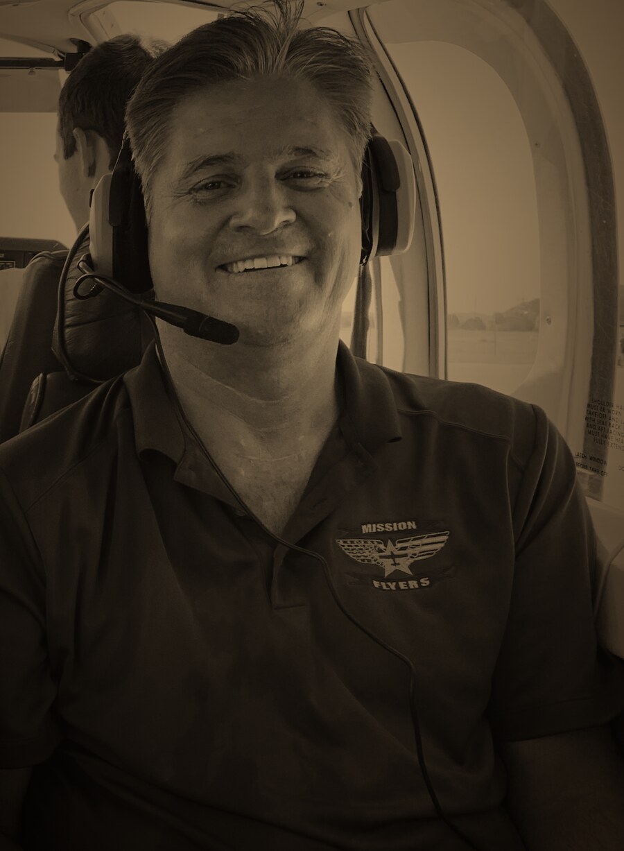 Richard Vietor, smiling, in the warm graded light of a small aircraft cabin.